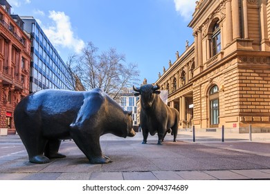 Place in front of the entrance to the Frankfurt Stock Exchange. Bull and bear as a symbol figure. Commercial buildings with a brown facade in the sunshine and blue sky with clouds in spring