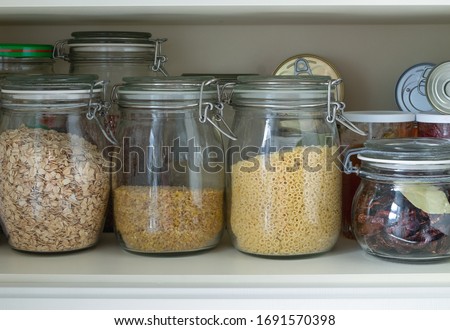 Place in a kitchen cupboard or pantry to store a stock of long-term food. Glass jars with cereals and pasta, canned goods. Horizontal orientation. Selective focus.