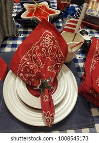 Place setting for a cowboy cookout with denium placemats and bandana napkins and an American flag