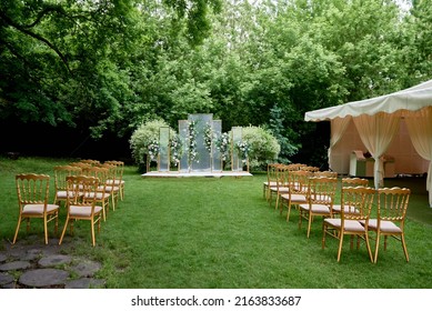 Place for wedding ceremony in garden outdoors, copy space. Wedding arch decorated with flowers and chairs on each side of archway. Wedding setting - Powered by Shutterstock