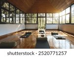 Place for yoga exercises group meditation practices retreats sessions background in natural forest garden area building. Empty clean yoga gym room studio interior with big windows mats on wooden floor