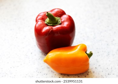 Placed on a countertop are a vibrant red bell pepper alongside a bright yellow bell pepper, showcasing their natural beauty and freshness - Powered by Shutterstock