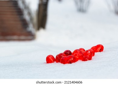 Placer of small bright red glass hearts on powdery snow of snowdrift by stairs at cold winter day, symbol of romantic love, St. Valentine's Day holiday concept