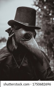A plague doctor with a cane and a classic dark garb with a cross - Shutterstock ID 1750682696