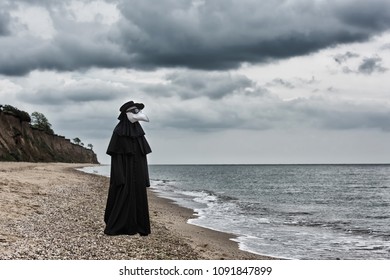 Plague Doctor In Seaside. Outdoor Portrait With Dramatic Sky In Background.