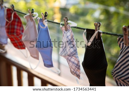 A Plaid fabric face shield are drying with other colorful facemask in the drying rope. This is new normal and impacted by COVID-19.