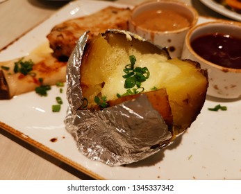 Plain Baked Potato On Dish With Some Food.
