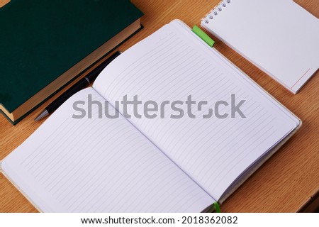 Plain Blank Open Notebooks With Stack Of Pens Inside Container Placed On Top Of A Table. Simple Empty Lined Notepads Beside A Holder Of Colorful Ballpens On A Desk.