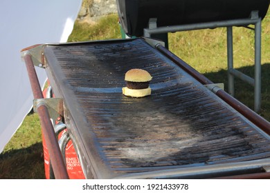 A Plain Burger Left Alone On A BBQ In Summer.