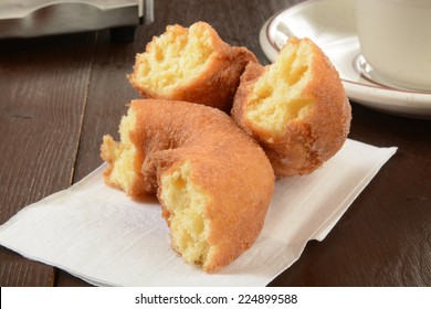 A Plain Cake Donut Broken In Half With A Cup Of Coffee