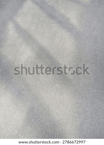 Plain Concrete Surface With Soft Diagonal Shadows And Faint Cracks Outdoors Showing Subtle Texture And Tonal Variations On Pavement In Natural Light.