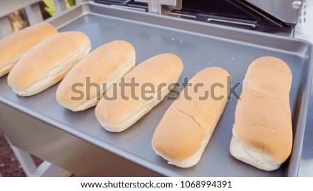 Plain hot dog buns on the cooking tray ready to be warm up on outdoor gas grill.