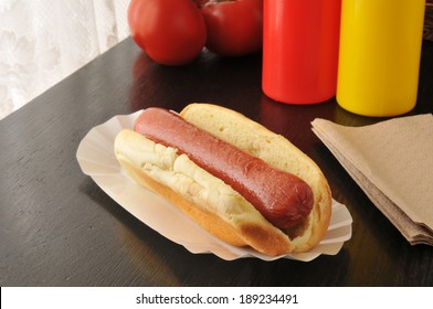 A Plain Hot Dog On A Bun On A Table By The Window