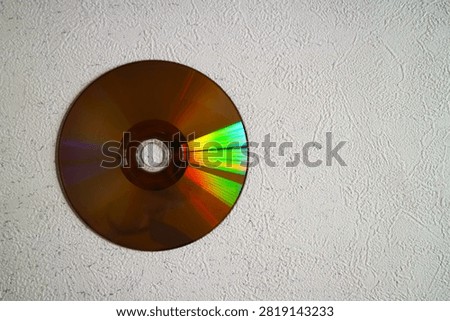 A plain optical disc (for storing CD or DVD data) displaying a rainbow like color effect caused by light reflection.