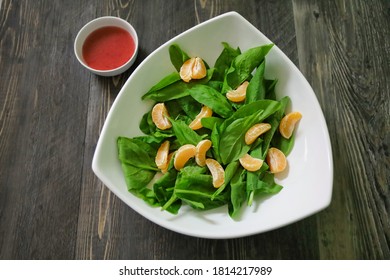 A Plain Salad With Baby Spinach, Mandarin Oranges And Raspberry Vinaigrette Dressing On The Side.