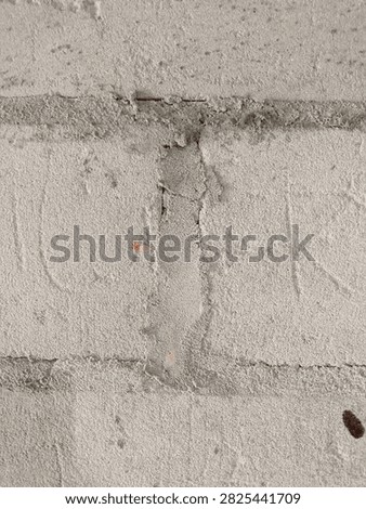 A plain, unpainted cinder block wall with visible mortar lines, presenting a simple, functional, and rugged industrial texture.