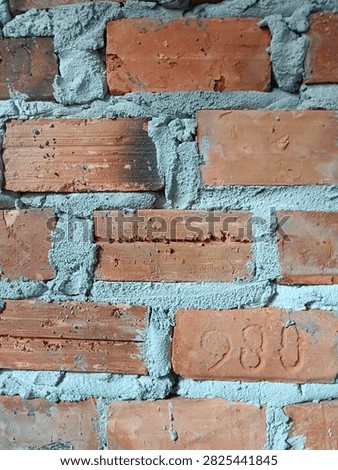 A plain, unpainted cinder block wall with visible mortar lines, presenting a simple, functional, and rugged industrial texture.