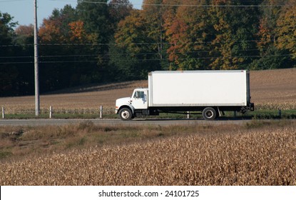 A Plain White Cube Van Speeding On A Road During The Harvest.