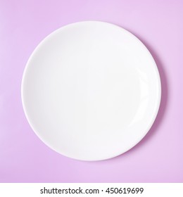 A Plain White Dinner Plate On A Pink Background