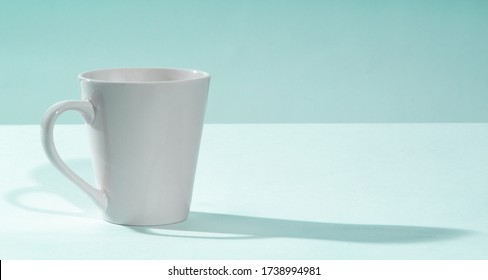 Plain White Mug Sitting On A Light Blue Table With A Blue Backdrop