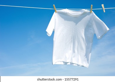 A Plain White T-shirt Hanging On A Clothesline On A Beautiful, Sunny Day, Add Text Or Graphic To Shirts Or Copy Space