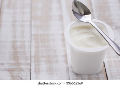 Plain Yogurt In White Plastic Cup On Wooden White Background. White Yogurt. 