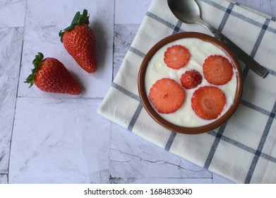plain yogut with fresh strawberries in clay pot