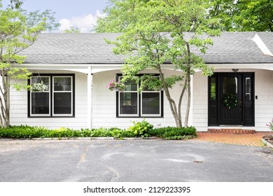 PLAINFIELD, IL, USA - JULY 15, 2021: A beautiful farmhouse ranch with white siding and a black front door.