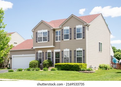 PLAINFIELD, IL, USA - MAY 23, 2022: A suburban house with brown siding, a red roof, and a two car garage.