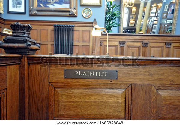 Plaintiff\'s seat within a court room, no\
people, traditional wooden\
courtroom