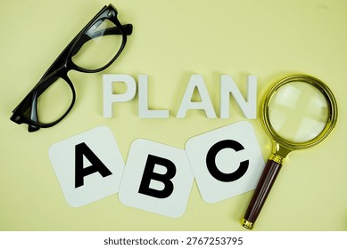 Plan A, Plan B, Plan C with eye glasses and magnifying glass on yellow background