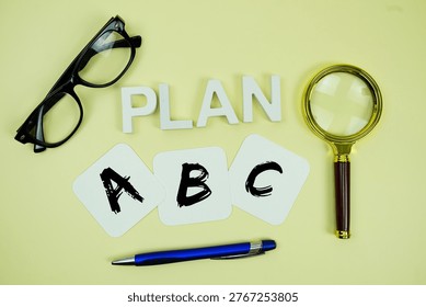 Plan A, Plan B, Plan C with eye glasses and magnifying glass on yellow background