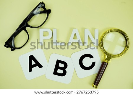 Plan A, Plan B, Plan C with eye glasses and magnifying glass on yellow background