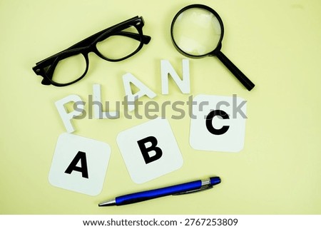 Plan A, Plan B, Plan C with eye glasses and magnifying glass on yellow background