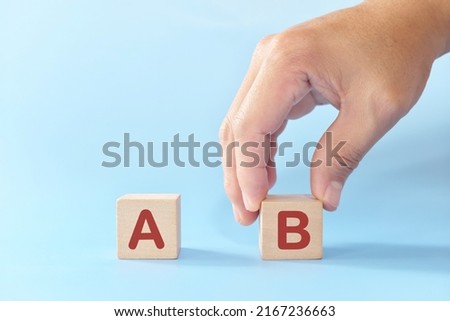 Plan B or backup and contingency plan in business concept. Hand choosing B versus A in wooden blocks in blue background. 