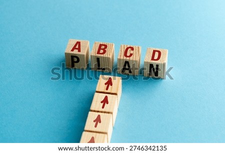 PLAN A B C D text on wooden blocks with red arrows on a blue background for business strategy, risk management, and alternative solutions concept.