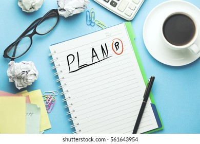 plan b text writeen on notebook with coffee,calculator and coffee on blue background