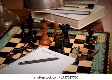 plan ready to be written things to do today note book on the chess board books pen watch and a lamp on the wooden table