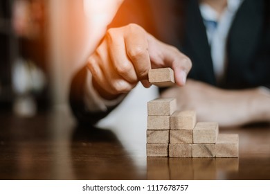 plan and strategy in business.risk concept.hand of man has piling up and stacking a wooden block.Businessman Building The Success.