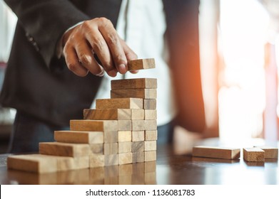 plan and strategy in business.risk concept.hand of man has piling up and stacking a wooden block.Businessman Building The Success. - Shutterstock ID 1136081783