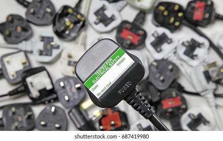 plan view of plugs – Blurred background of  three pin plugs with top of plug  with test sticker