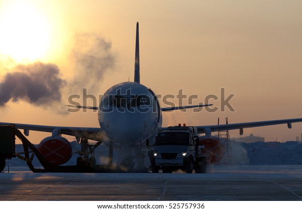Plane at the airport at sunrise in the early winter\
morning. Preparing for the departure of the aircraft on a strong\
frost. Airplane front\
view.