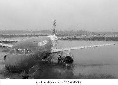 Plane before flight through blurred window with raindrops. Plane black and white. Avaition concept. Travel and transport background. Rainy day in airport. 