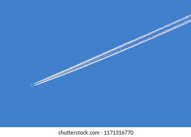 Plane With Condensation Trail In Front Of Blue Sky