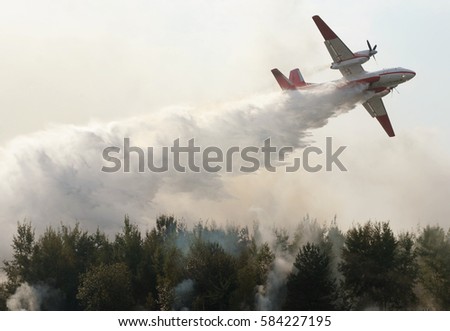 plane drops fire retardant and water on a forest fire