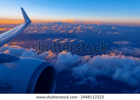 Plane engine and wing gracefully soar over clouds during the evening. Flying over Canary Islands in Atlantic Ocean 