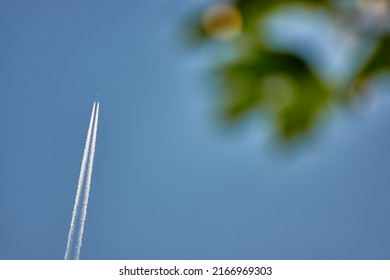 Plane flies across clear, cloudless sky and leaves double Trace.