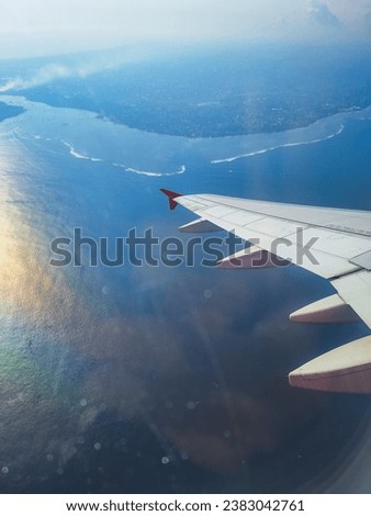 Plane flying above a tropical island. Aircraft soaring above the blue ocean. Clear view from a high altitude. Unparalleled natural beauty. Spectacular view from above the plane. Tropical Island Bali.