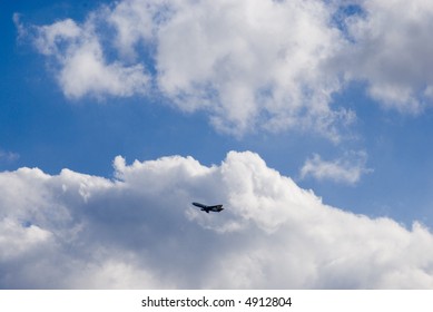 plane flying between clouds on a sunny day
