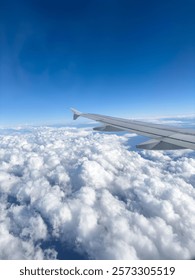 Plane flying over clouds, view from airplane window, fluffy cloudscape and blue sky background